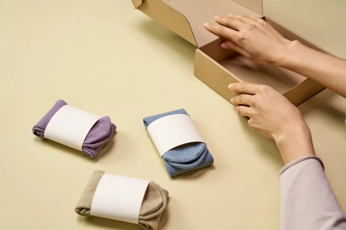 Hands packing folded pieces into a box to ship