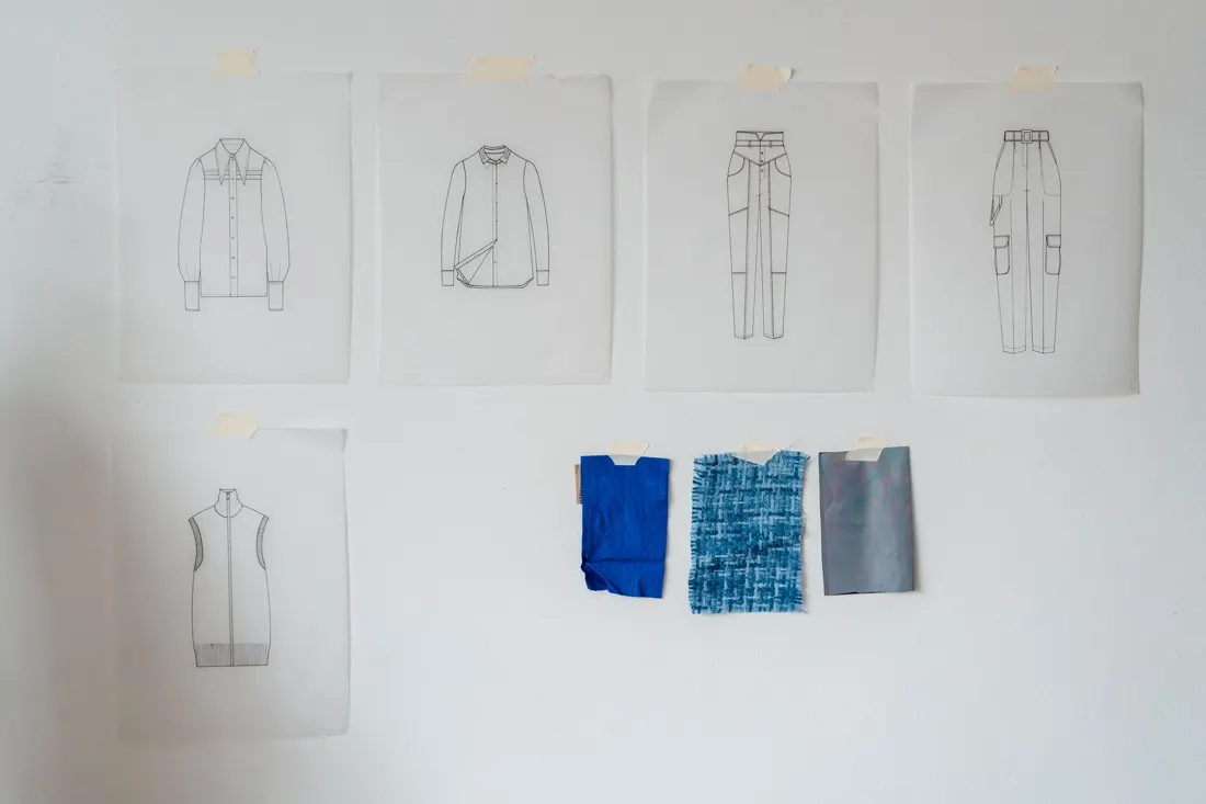 Garment sketches and flats pinned on a studio wall