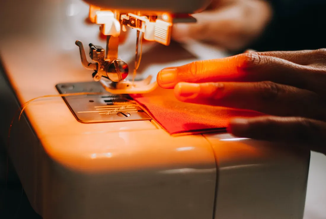 A sewing machine stitching fabric under warm light