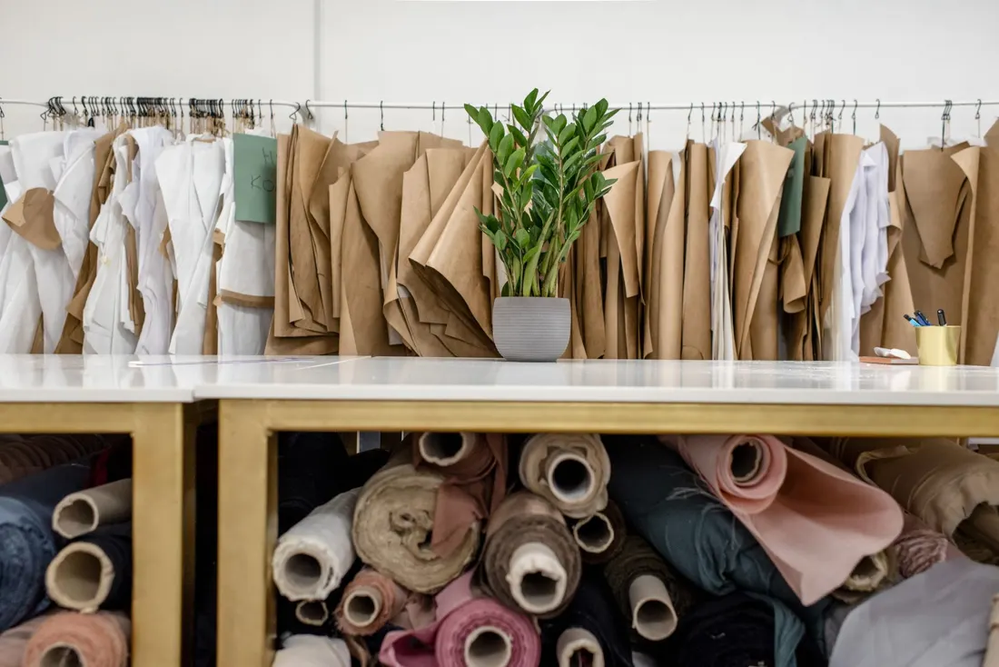 Rolls of fabric and finished pieces on a studio shelf