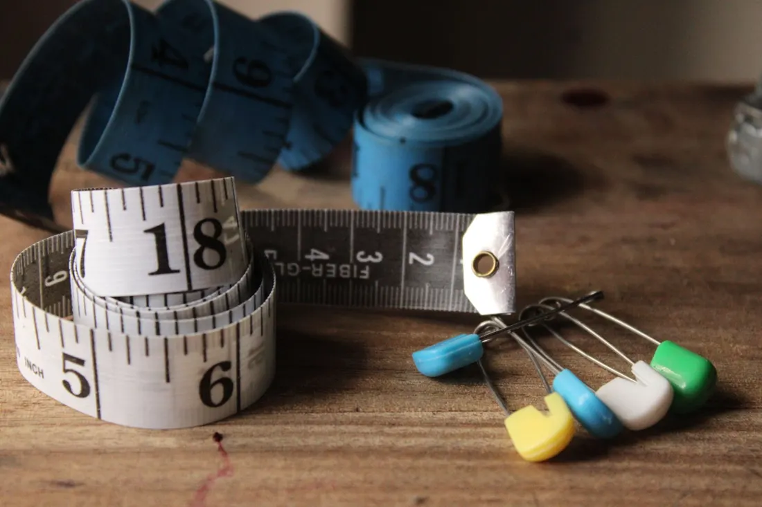 Tape measures and sewing pins on a wooden table